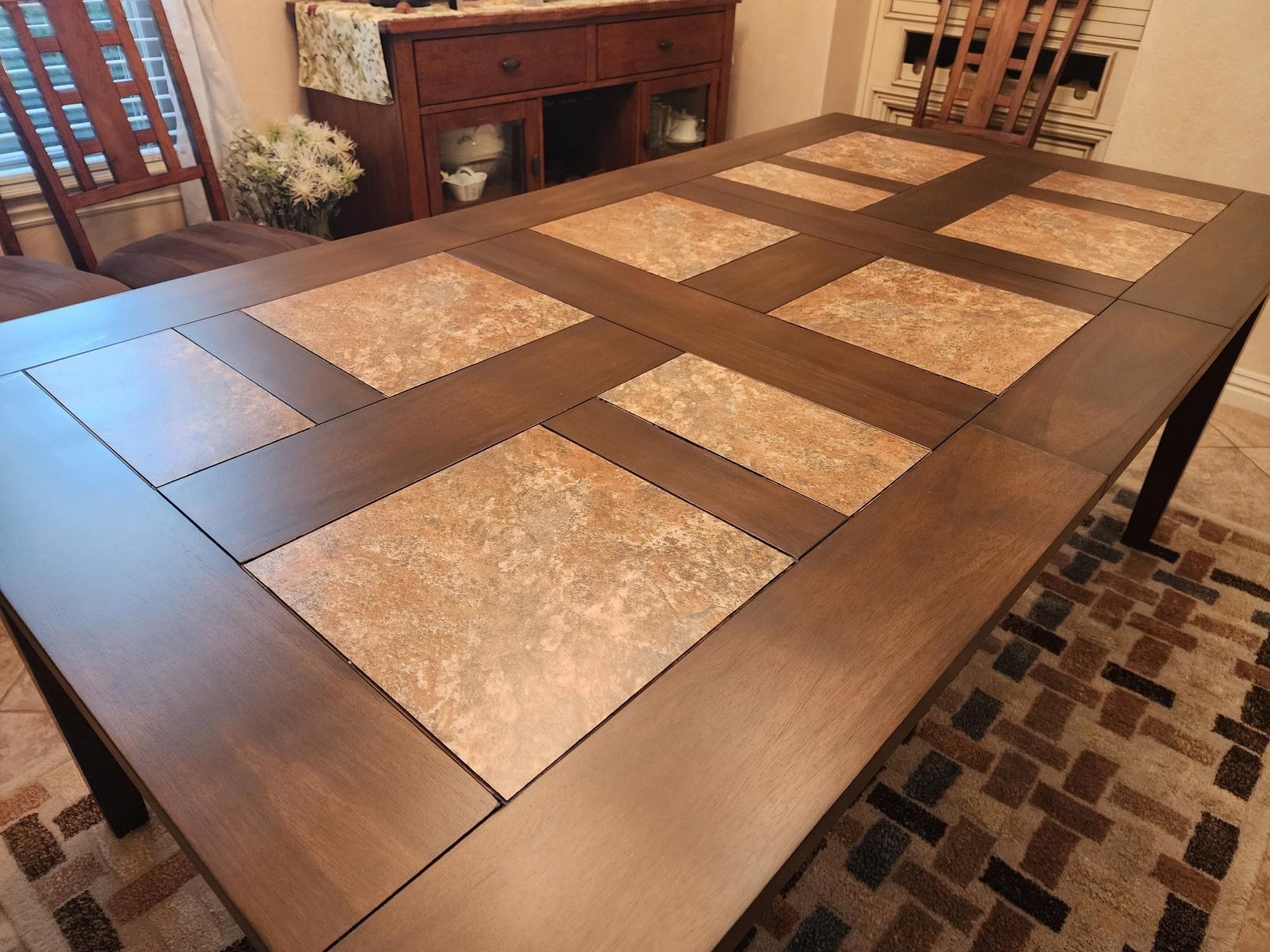 Refinished dining table with a geometric grid of decorative tile inlays