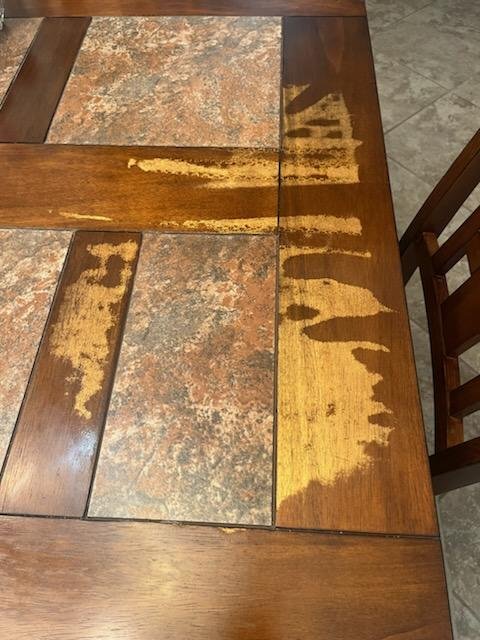 Dining table with tile inlays showing heavy finish damage before refinishing